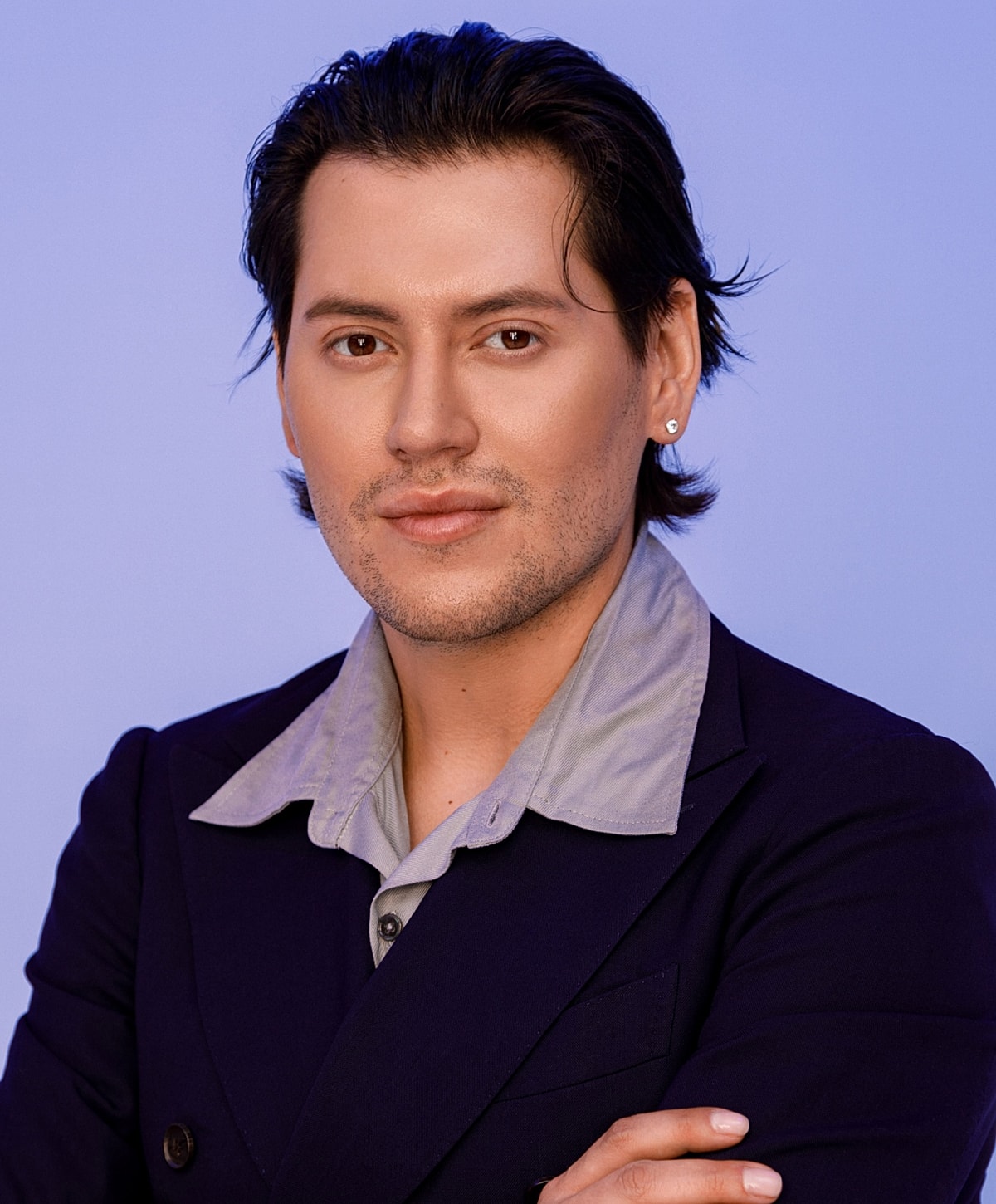 Person posing confidently against a blue background.