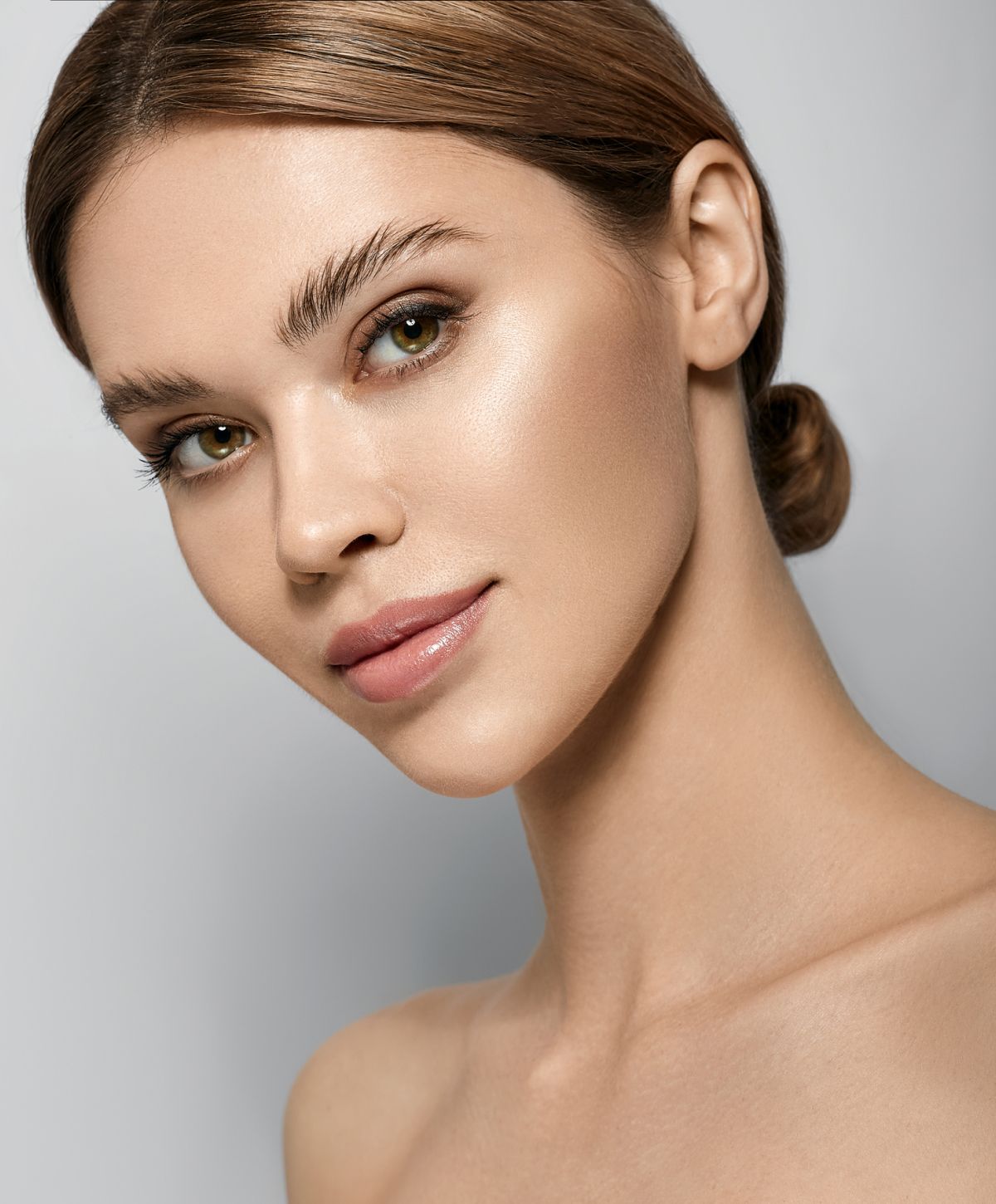 Woman with natural makeup and glossy skin.